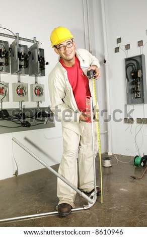 Electrician bending conduit pipe on the job.  Actual electrician performing work according to national code and safety standards.  (writing on bender is instructions, not trademark)