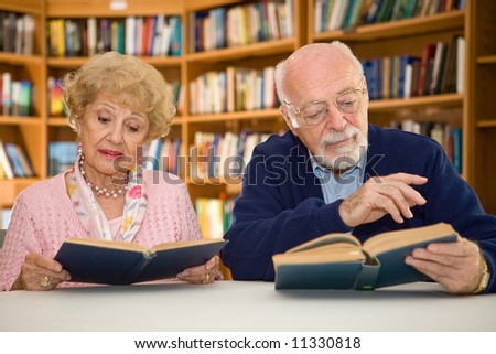 Senior couple together reading at the library.