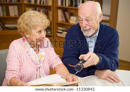 Senior man and woman meeting at the library and discussing books.