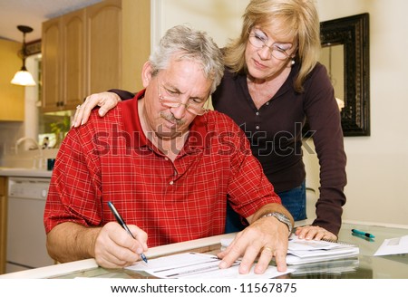 Mature couple in financial trouble is filling out a loan application.