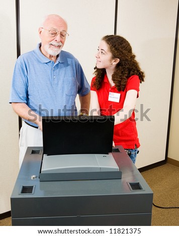 Volunteer explains new optical scan voting machine to a senior on election day.