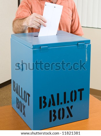 Closeup of a man\'s hand placing his ballot in the box.