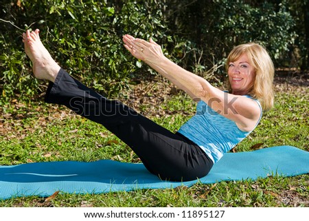 Amazingly fit sixty year old woman doing pilates, demonstrates her core strength while smiling at the camera.