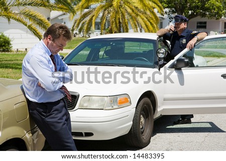 Embarrassed looking businessman pulled over by the police.  Focus is on the businessman.