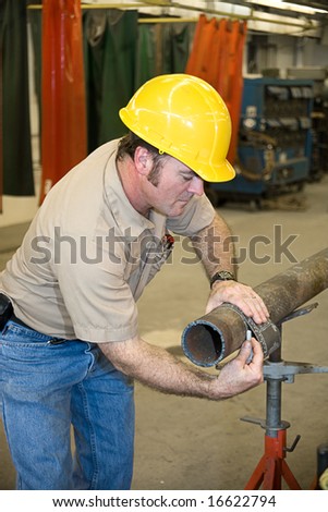 Metal worker using a flexible ruler to measure pipe and mark it for cutting.  Authentic and accurate content depiction in accordance with industry code and safety standards.