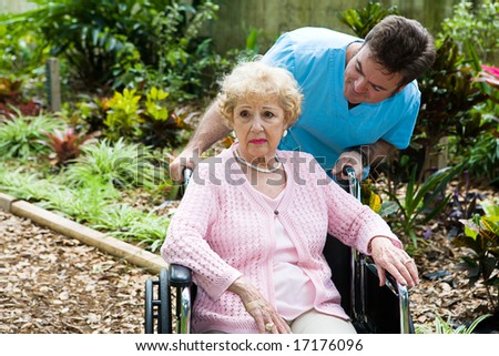 Senior woman in nursing home is feeling depressed and forgotten.  Her orderly tries to comfort her.