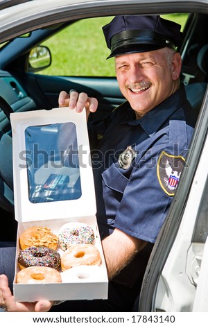 Police officer sitting in his squad car with a box of donuts.
