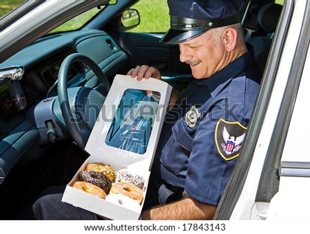 Policeman in his squad car, hungrily looking at a box of donuts.
