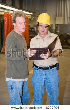 Auditor discussing his report with a factory foreman.