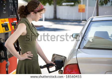 Teen girl at the gas station filling up the fuel tank in her gas efficient car.