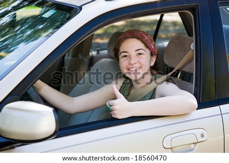Cute teen driver giving the thumbs up after passing her driving test.