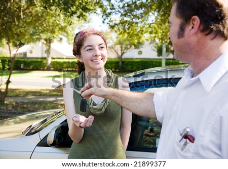 Young woman being handed the car keys by her father or driving instructor.