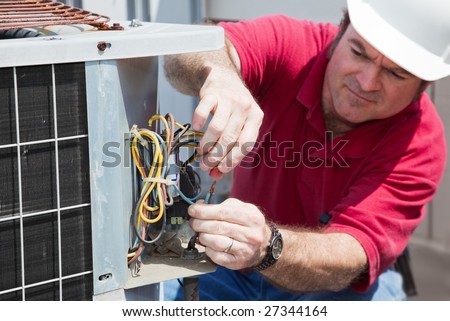 Air conditioning repairman rewiring a compressor unit.  Focus on the man\'s hands and the wires.