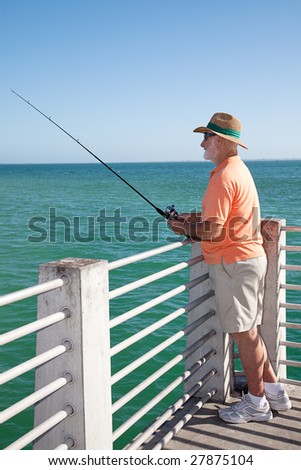 Retired senior man enjoys fishing from a pier into the ocean.