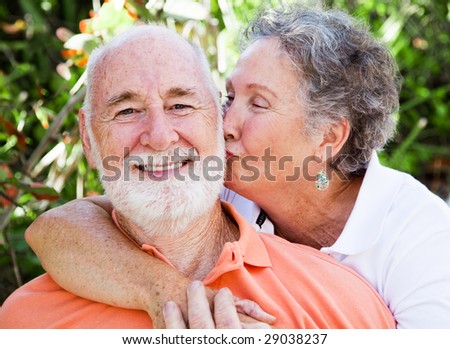 Senior woman giving her husband a kiss on the cheek.