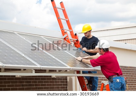 Workers install energy efficient solar panels on the roof of a building.