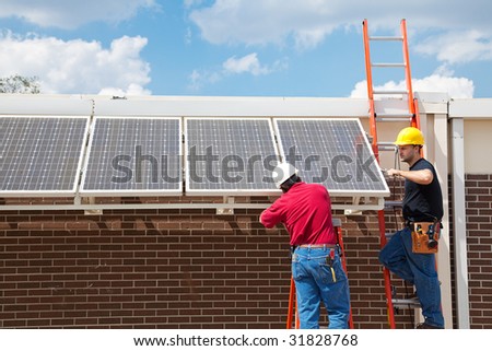 stock photo : Workers installing solar panels on the side of a building.