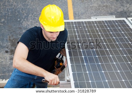Electrician installs solar panels on the side of a building.
