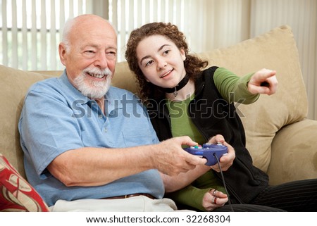 Teen girl shows her grandfather how to play video games.