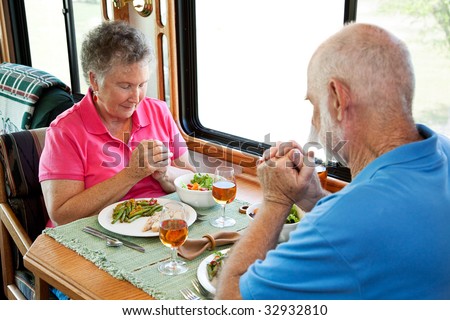 Christian senior couple saying grace over a meal in their motor home.