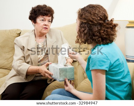 Understanding therapist handing tissue box to an upset teen patient.