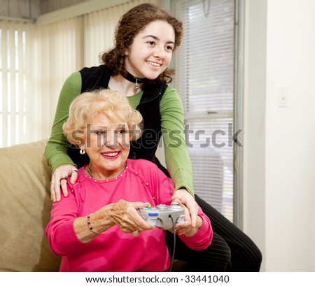Teen girl teaching her grandmother how to play video games.  Fun family moment.