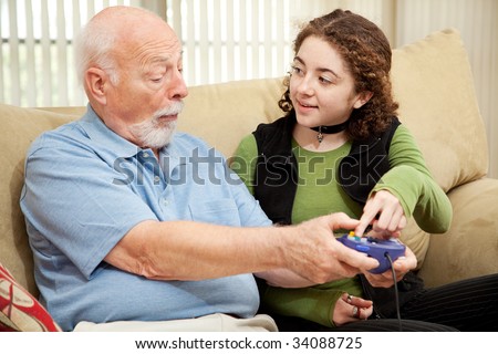Teen girl teaching her grandfather how to play video games.