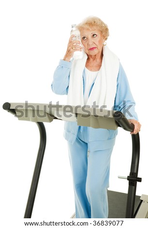 Senior woman on a treadmill cools down with bottled water.  Isolated on white.