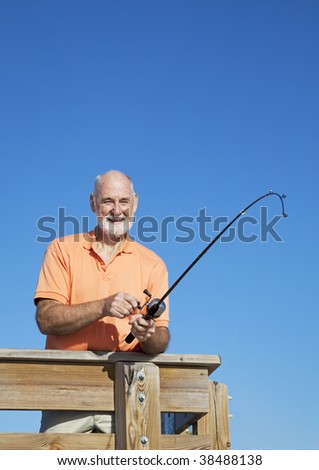 Retired senior man fishing off a pier.  Vertical view with room for text.