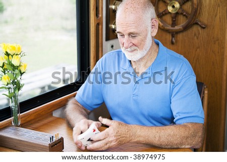 Senior man in his RV, shuffling cards to play cribbage.  Motion blur on the cards.