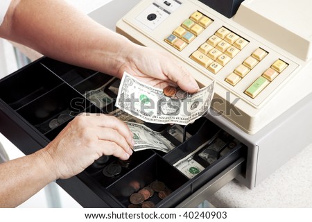 Horizontal view of an open cash register drawer asa a cashier makes change.