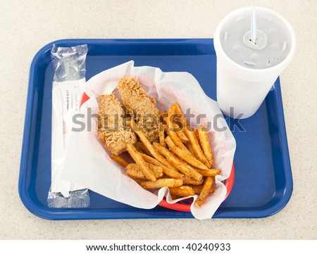 Fast food tray holding a basket of fried chicken, french fries, and a styrofoam cup of soda.