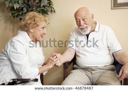 Senior couple in the waiting room of the doctor\'s office holding hands for moral support.