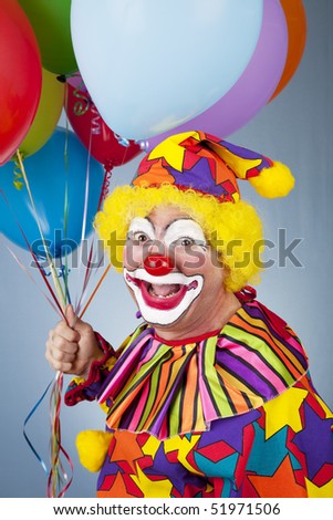 Portrait of happy clown holding a bunch of helium balloons.