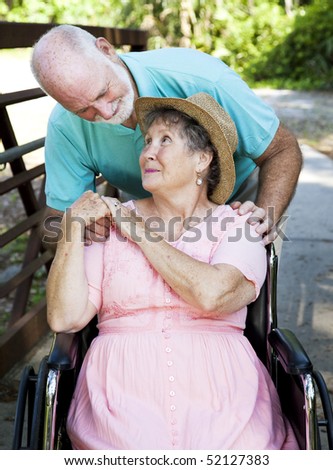 Senior man caring for his disabled wife.