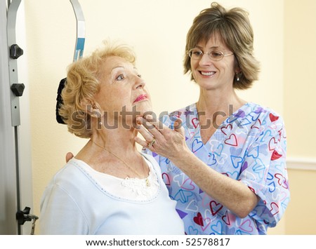 Physical therapist in chiropractors office helping a senior woman exercise her neck.