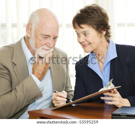 Senior man reading and thinking about a contract while eager businesswoman encourages him to sign.
