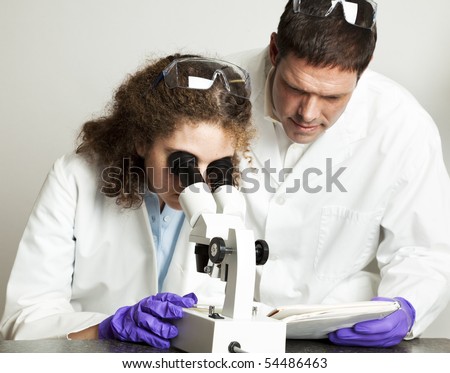 College (or high school) student working in science lab.  Her teacher is looking over her notes.