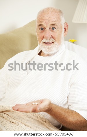 Senior man sick in bed doesn\'t want to take his medicine.