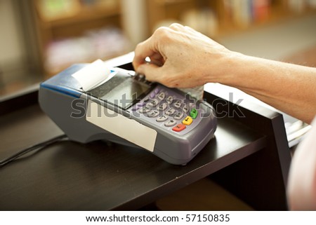 Closeup of a credit card scanning machine in use.  Shallow depth of field.