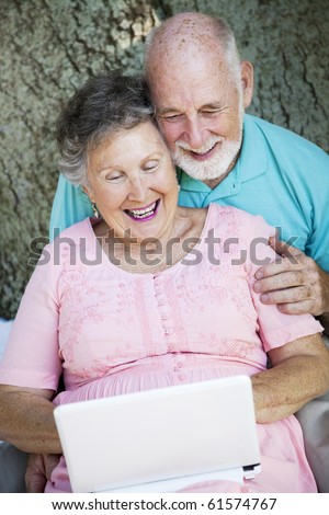 Senior couple stays in touch with the grandchildren using a small netbook laptop computer.