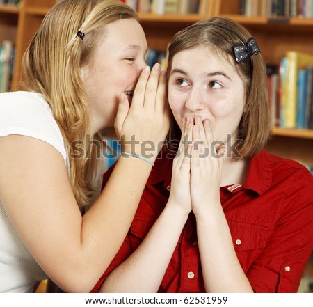 School girl whispers a shocking secret to her friend.