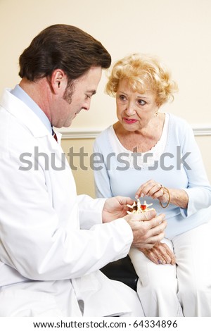 Chiropractor shows senior patient a model of the spine and discusses her treatment plan.