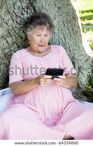 Confused senior woman struggles to understand how to text on her new smart phone.