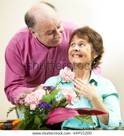 Handsome mature man presents flowers to his beautiful wife.