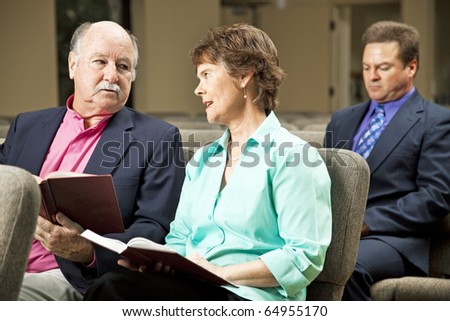 Mature couple sitting in church holding hymnals.