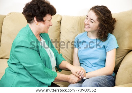 Mother and teenage daughter having a conversation together on the couch.