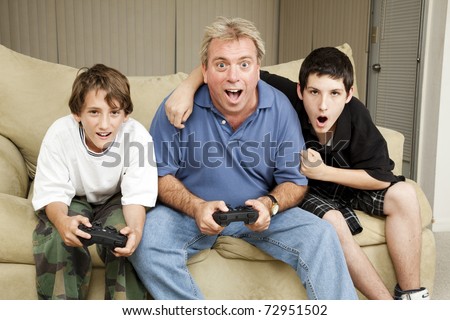 Uncle playing video games with his nephews.  Could also be dad and sons.