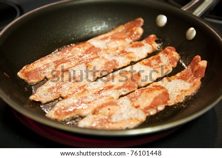 Cooking slices of healthy, low fat turkey bacon in a frying pan.  Shallow depth of field.
