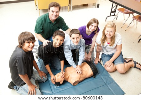 A group of teenage students learning CPR life saving techniques in class.